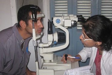 A patient recieving an eye test looking into a digital retina camera